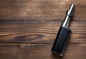 cigarette elcetronique posé sur un support en bois