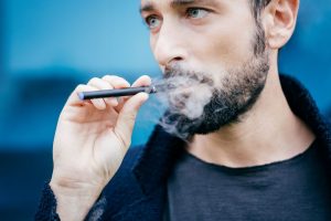Portrait d'une homme fumant une cigarette électronique