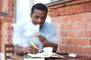 Jeune homme en train de vapoter sa cigarette électronique