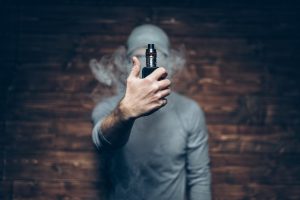 Jeune homme tenant la résistance de sa cigarette électronique