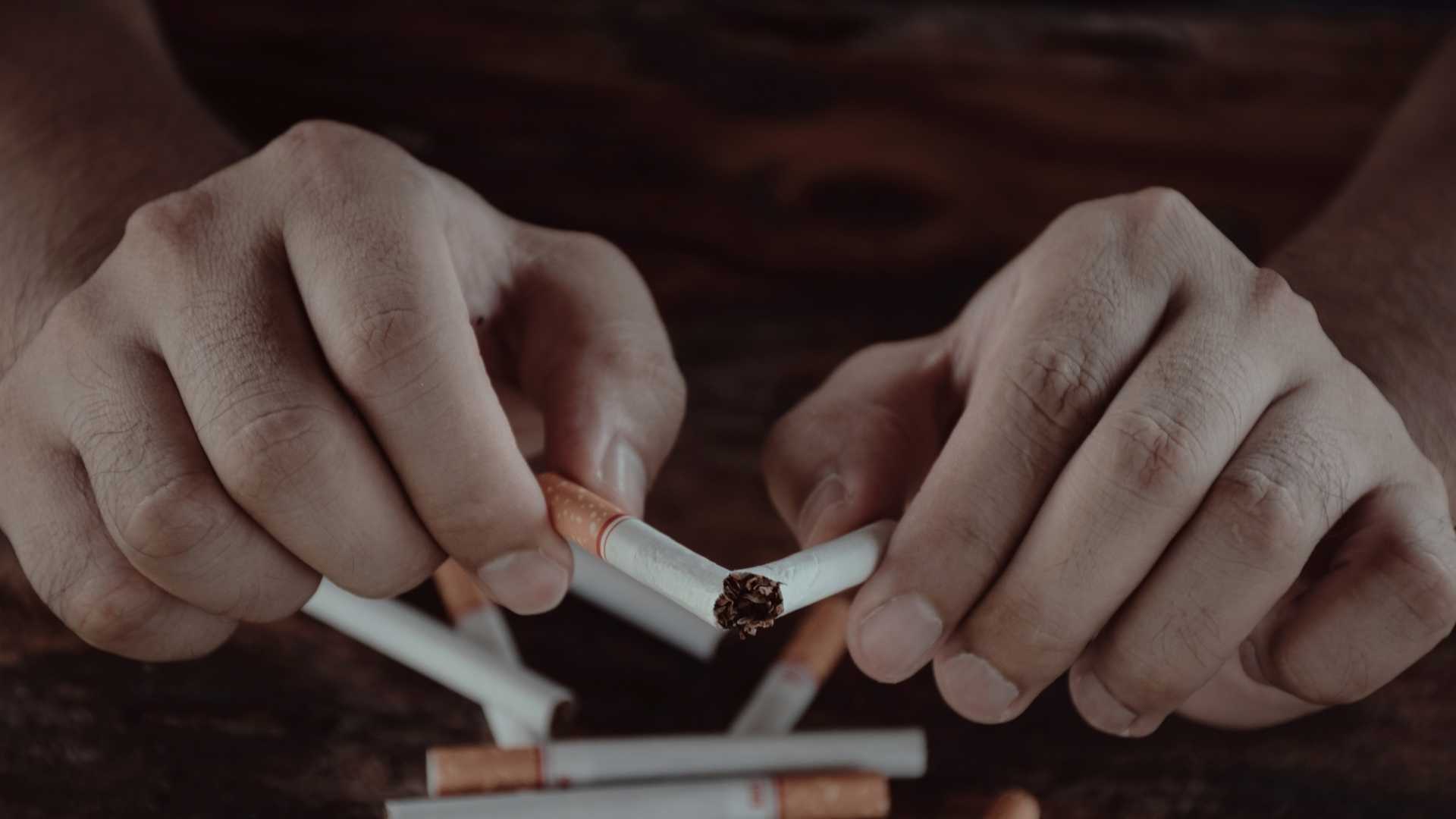 Homme qui casse ses cigarettes en deux